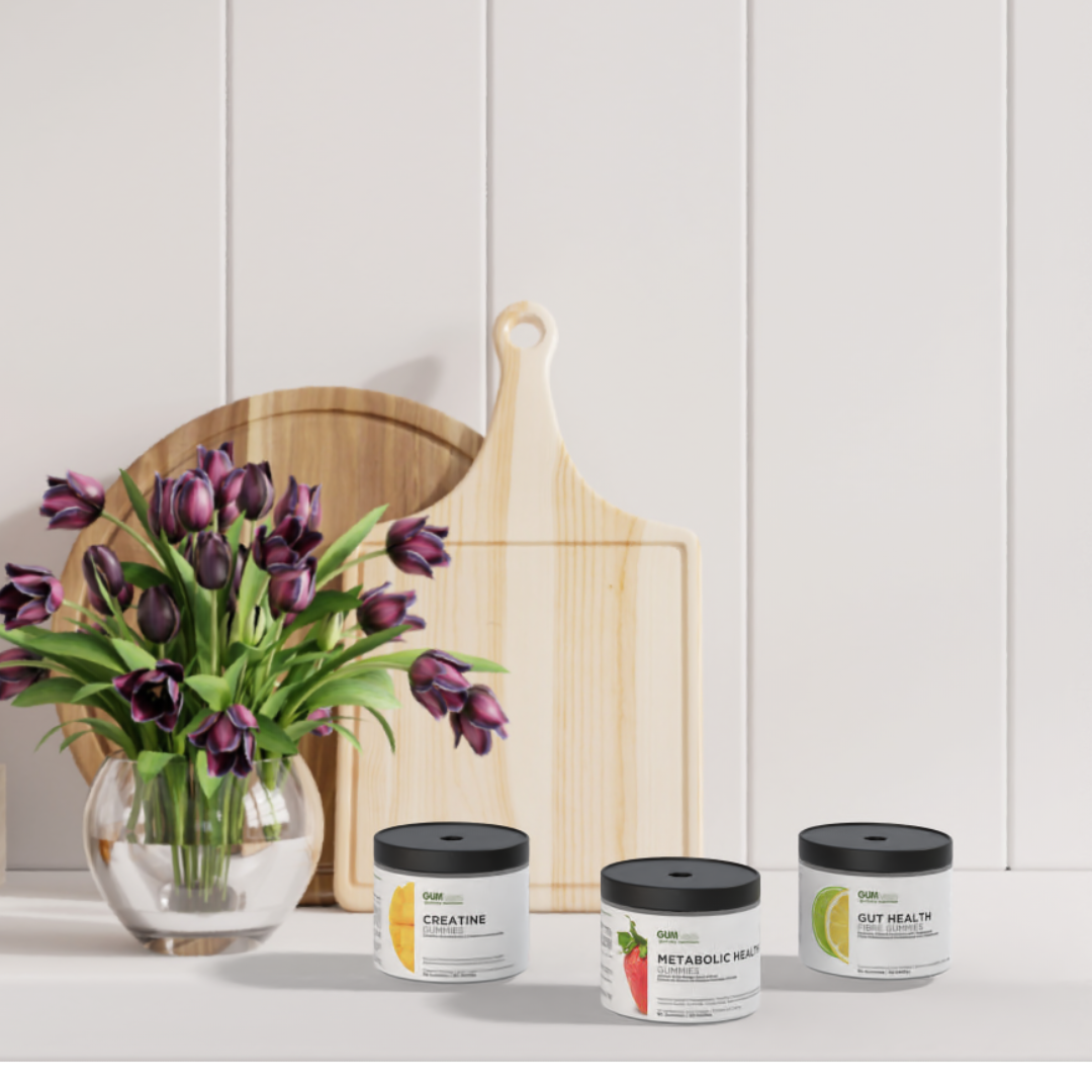 success pack gumv'ees creatine, metabolic health, and git health sit on a white kitchen counter in front of a vase of black tulips and two wooden cutting boards